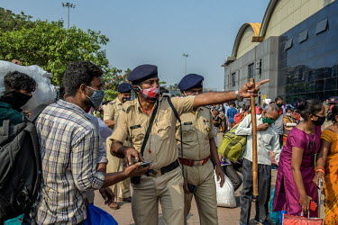 A policemen directs migrant workers outside the Lokmanya Tilak Terminus (LTT) station to where they can get a train departing to their home towns after it became clear that the local government was co...
