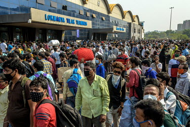 Migrant workers queue outside the Lokmanya Tilak Terminus (LTT) station to get to a train departing to their home towns after it was announced that the local government was implementing a complete loc...