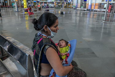 Seema Bai, waits with her child, for her lateral flow COVID-19 antigent test results at the CST Railway station where health workers were testing all arriving passengers.