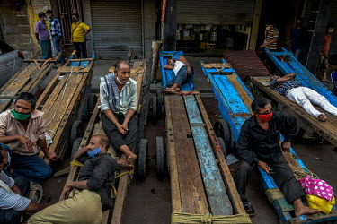 Day labourer porters sit on their hand carts close to the Mangal Das cloth market where all the non-essential goods shops were closed because of the second lockdown.