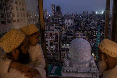 A Dawoodi Bohra Muslim family look out of their window at their local mosque after offering Friday Ramadan prayers at home rather than the mosque because of the second lockdown being implemented acros...
