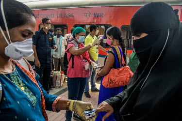 Health workers take people's temperatures and measures their oxygen saturation levels at the Dadar railway station while carrying out tests for COVID-19 on passengers arriving by train from outside th...