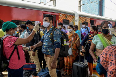 Health workers take people's temperatures and measures their oxygen saturation levels at the Dadar railway station while carrying out tests for COVID-19 on passengers arriving by train from outside th...