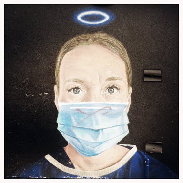 A mural of a nurse in scrubs wearing a face mask and with an Angel's halo, by AKSE in the Northern Quarter.