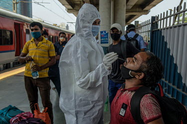 A health worker swabs a man's nose while carrying out lateral flow antigen COVID-19 rapid tests on passengers arriving from outside of the city at Dadar railway station.