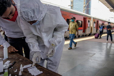 A health worker and a man check the a result after carrying out lateral flow antigen COVID-19 rapid tests on passengers arriving from outside of the city at Dadar railway station.