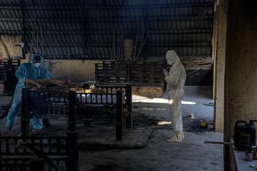 Relatives wearing white hazmat suits (PPE), and a funeral worker in blue, place the corpse of a man who died of COVID-19 onto a funeral pyre at the Hindu cremation ground on the outskirts of Mumbai.