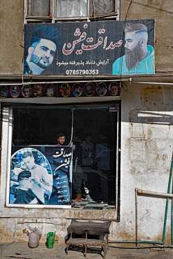 A youth looks out from a barbershop in the old city.