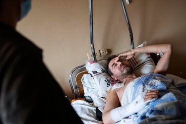 Sergei Denisiuk lies in a bed in a civilian hospital where he is finally getting medical care after being admitted the day before. He was shot three times outside his house in Moschun by Russian soldi...
