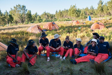 Members of a high-angle tree clearing team relax before dinner at their campsite in a remote montane catchment area that feeds the Theewaterskloof dam. From left: Thuliswa Sigxonono, Khanyisa Mzayifan...