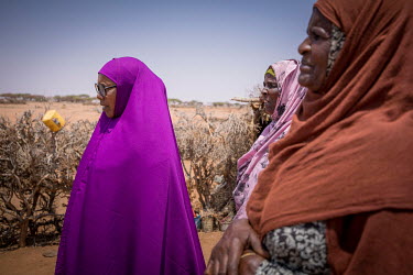 Local volunteer, Ibado (purple) talks with people, including Dehabo Hassan Darror (right), while on her daily rounds visiting IDPs displaced by drought in a camp near Oog.