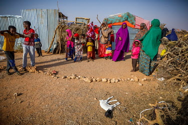 Local volunteer, Ibado (purple) stands near a dead lamb, that died early in the day, while she talks with women outside their makeshift shelters while on her daily rounds visiting IDPs displaced by dr...