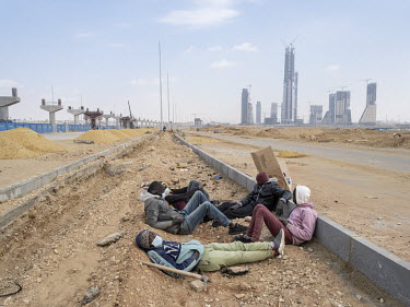 Migrant workers from South Sudan having a break near the towers of the Central Business District in Egypt's New Administrative Capital. Following persistent problems of overpopulation, pollution and t...