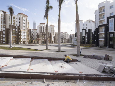 A young worker placing tiles on a square in the Third Residential Neighbourhood (R3) in Egypt's New Administrative Capital.~Following persistent problems of overpopulation, pollution and traffic conge...