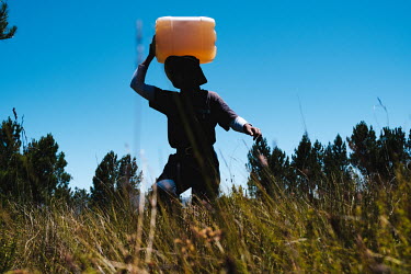 Thuliswa Sigxonono, a member of a high-angle tree clearing team, carrying drinking water from a stream back to camp after having been deployed to a remote montane watershed that feeds the Theewaterskl...
