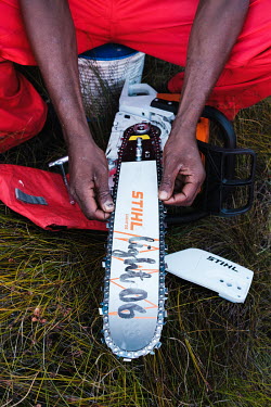 Sibongile Dyantyi, a members of a high-angle tree clearing team, checking his chainsaw in preparation for the following day's work, at his team's campsite in a remote montane catchment area that feeds...