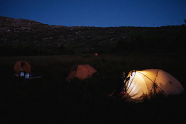 Alungile Mayekiso, a member of a high-angle tree clearing team, beside her tent as night falls over the team's campsite in a remote montane catchment area that feeds the Theewaterskloof dam. The teams...