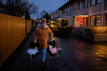 Drifa Hrund Guomundsdottir carries her twins through the outskirts of Reykjavik on a cold winter day after they went for a doctor's appointment and visited a grocery shop.