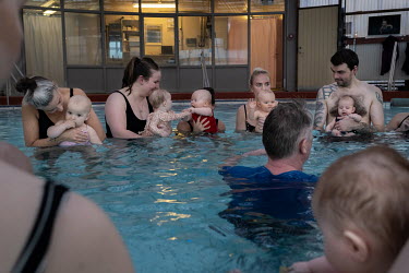 A group of men and women with their babies with teacher Snorri Magnusson during a parent and child session in a swimming pool. Snorri Magnusson started giving swimming lessons for babies in 1990. Curr...