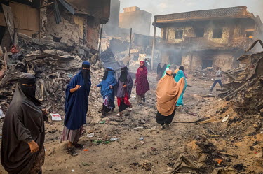 A group of women walk among charred remains of the Waheen market after a huge fire tore through what was home to an estimated 2,000 shops and stalls. According to officials about two dozen people were...
