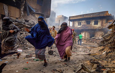A group of women walk among charred remains of the Waheen market after a huge fire tore through what was home to an estimated 2,000 shops and stalls. According to officials about two dozen people were...