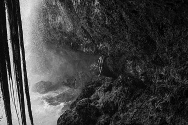 Mailon Araxi, a young indigenous Manoki, crosses the Cravari River beneath a waterfall on Irantxe Indigenous Land. Inhabiting the transition between tropical savanna (the Cerrado) and Amazon forest, t...