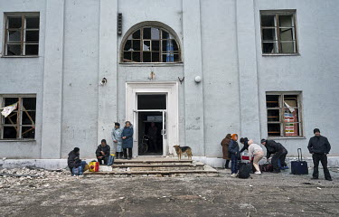 People wait outside the House of Culture where they have gathered to get transport out of the city using evacuation minibuses organised by volunteers from SOS Vostok.
