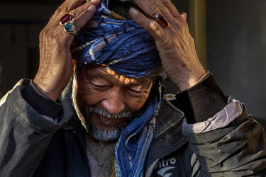 A man adjusts his turban in a bazaar.
