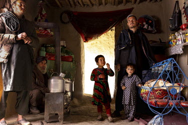 Twaos Khan (squatting at left), the manager of a camp for displaced people who came from Helmand 20 years ago, breaks bread at his home. Only 17 families have returned to Helmand from the camp, the re...