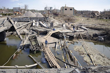Local civilians cross the River Irpin (Irpen) via planks that were laid beside the original bridge, connecting the commuter town to the capital, destroyed by Ukrainian defenders to prevent its use by...