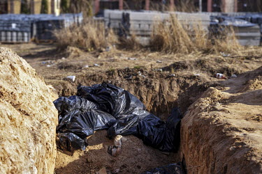Black plastic body bags containing corpses lie in a mass grave outside the church of St Andrew in Bucha.