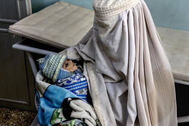 A woman holds a malnourished child as she waits to be seen by medical staff at Mirwais Regional Hospital. For the past few years, with the war and insecurity, the patients from the region, especially...