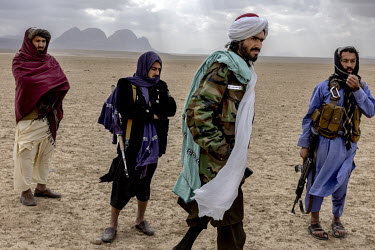 Taliban militia wait while two families in conflict over the use of their land speak to a Taliban official. One party wants to raise livestock and the other wants to plant wheat. The conflict has been...