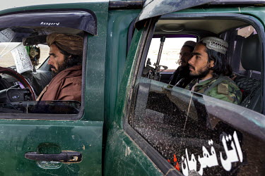 Taliban militia sitting in a car while a land dispute between two families is adjudicated nearby.