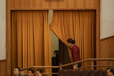 An attendant raises a curtain during the opening of the 19th National Congress of the Communist Party of China at the Great Hall of the People.