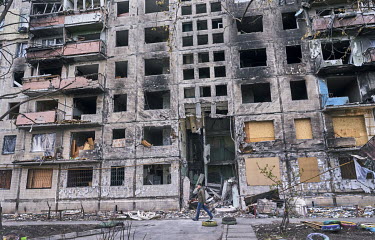 A man walks past a destroyed apartment block in the Obolon district. It was hit by a Russian shell in the early morning hours of 14 March 2022 killing two people and wounding many more.