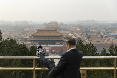A man stretches his leg while standing on top of Jingshan Hill overlooking the Forbidden City during the Chinese Communist Party's congress in the Great Hall of the People.