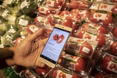 A shopper uses a smartphone at an Alibaba Group Holding Ltd's Hema or Fresh Hippo store.