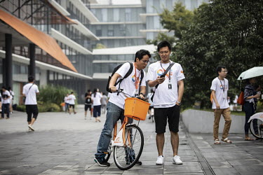 An employee stops to talk to a colleague while using a shared bicycles at the main campus of the Alibaba Group Holding Ltd. headquarters.