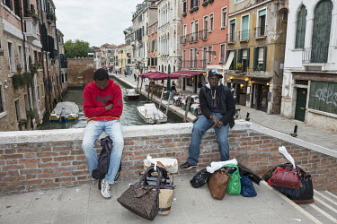 Senegalese migrants selling fake designer handbags on a canal bridge.