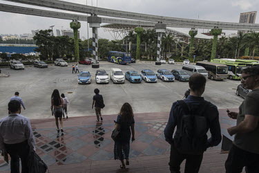 Visitors walk towards a line up of electric vehicles parked in a square at BYD (Build Your Dreams) headquarters.