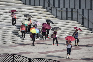 Villagers carrying umbrellas to shield them from the sun as they walk through a square in Huanggang village in Shenzhen. Several villages, including Huanggang, formed much what became the Shenzhen spe...