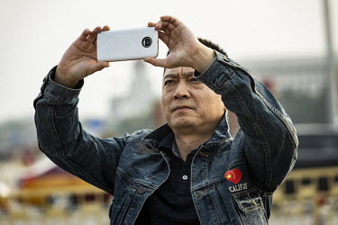 A visitor uses his smartphone to take a photograph in Tiananmen Square during the Chinese Communist Party's congress in the Great Hall of the People.
