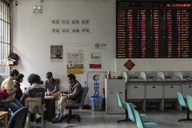 Retail investors standing sit beside the digital trading boards at a stock exchange house.