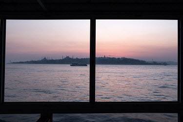A view of Istanbul's historic peninsula, home to the Hagia Sofia, Blue Mosque and other cultural attractions from a commuter ferry at dusk.