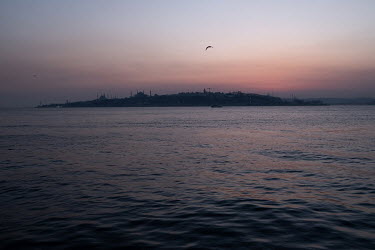 A view of Istanbul's historic peninsula, home to the Hagia Sofia, Blue Mosque and other cultural attractions from a commuter ferry at dusk.