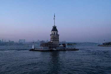 A view of Istanbul's maiden's tower with the business district of Levent in the background, from a commuter ferry at dusk.