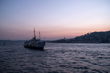 A view of a ferry off Istanbul's historic peninsula, home to the Hagia Sofia and other cultural attractions from a commuter ferry at dusk.