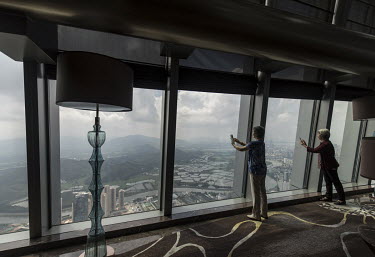 Visitors take photos of the view from a hotel restaurant high above the city.