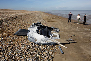 Locals photograph the remains of an inflatable boat used by migrants to cross the English Channel from France as it lies on Dungness Beach.